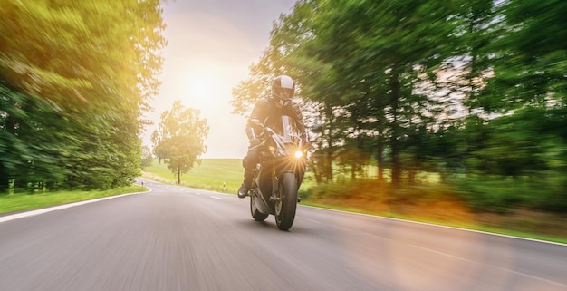 あなたの個々のテキストのためのオートバイ旅行のコピースペースで空の道を運転している道路に乗っているバイク