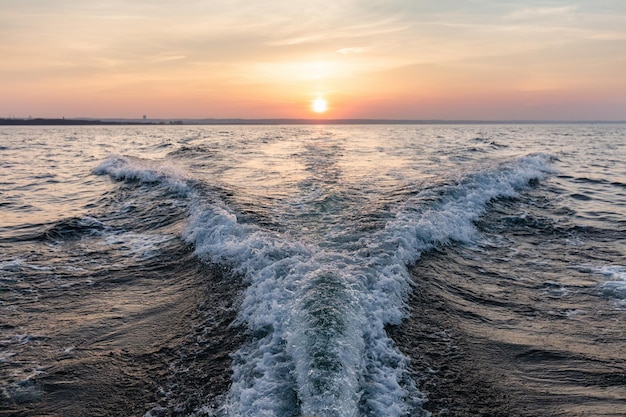 Motorboat wake pattern on sea at sunset