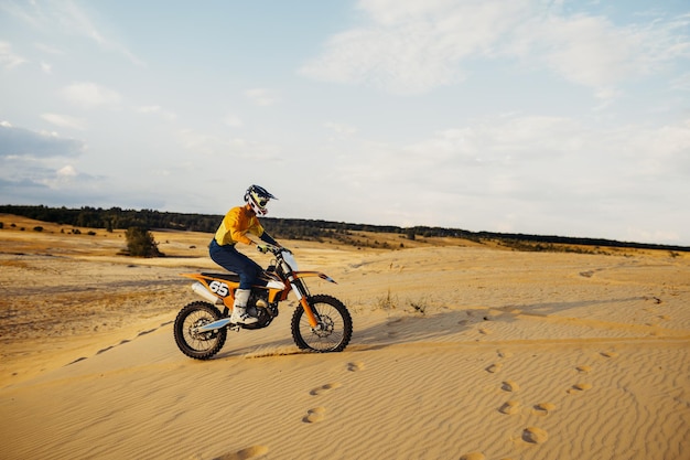 Motorcross riding over sand in desert dune