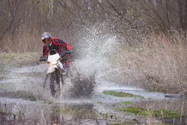 Motorcrosser racen in overstroomd bos in de lente