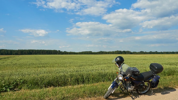 Photo a motorcycle on an empty dirt road with a wheat field in the background moto journey countryside