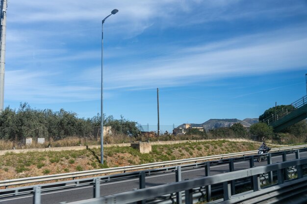 A motorcycle is riding down a road with a clear blue sky above