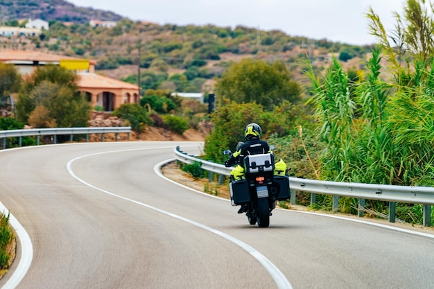 여름에 이탈리아 사르데냐 섬의 코스타 스메랄다(Costa Smeralda) 도로에서 오토바이. 유럽의 고속도로에서 스쿠터를 운전하는 오토바이 운전자. 고속도로에서 오토바이에 보기.