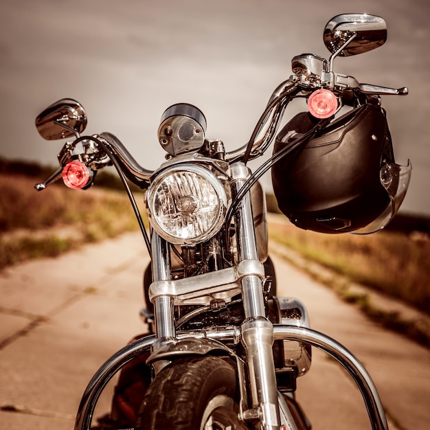 Motorcycle on the road with a helmet on the handlebars.