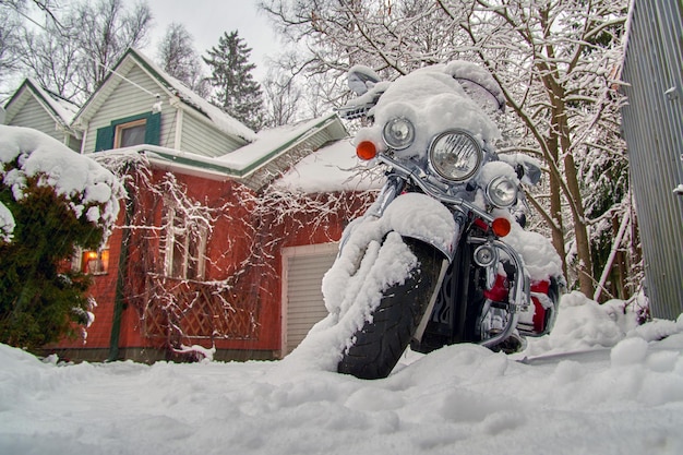 Motorcycle under the snow in the yard of the house