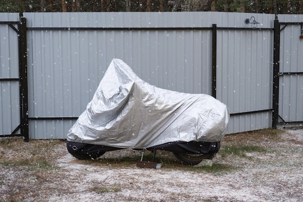 冬の屋外の日よけの下でのオートバイの保管 雪の下の保護日よけ