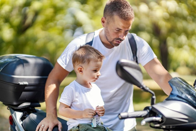 Foto motociclette e ragazzi il bambino è seduto sulla moto mentre papà lo tiene in braccio