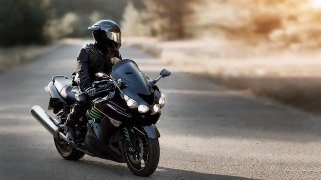 Motorcyclist in helmet rides on the road on modern black motorcycle. Sport bike. Copy space for your customized text. Motorcyclist in leather protective gear