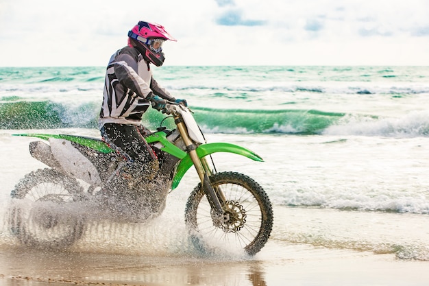 Motorcyclist in a protective suit rides a motorcycle on the seashore