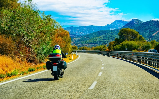 Foto motorfiets op de weg aan de costa smeralda op het eiland sardinië in italië in de zomer. motorrijder scooter rijden op snelweg van europa. man op bromfiets op snelweg. provincie olbiai. gemengde media.