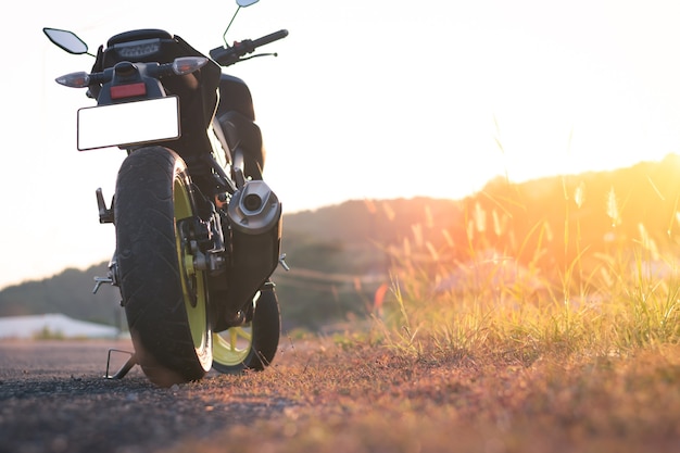 Motorfiets parkeren op de weg, vintage stijl met zonsonderganglicht, kopie specificatie voor individuele tekst, motor met natuurlandschap