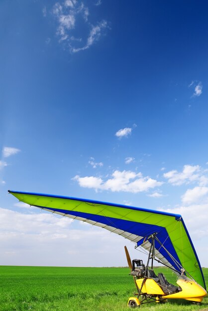 Motorized hang glider over green grass, ready to fly.