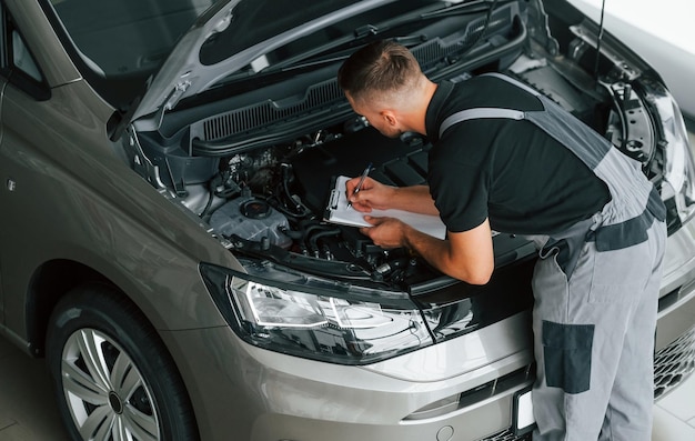 Foto motorreparatie man in uniform werkt overdag in de autosalon