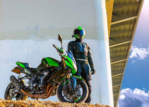 Motorrijder in een helm en in een beschermend pak staat onder de brug