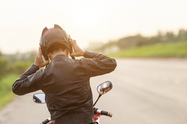 Motorrijder lederen jas dragen en helm op de weg houden