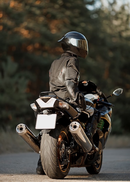 Motorrijder op zijn motorfiets op de weg. Man op een moderne sportfiets. Vrijheid en avontuur concept. Achteraanzicht dichten