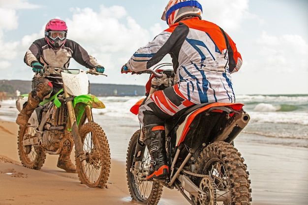 Motorrijders in een beschermend pak zittend op motoren tegenover elkaar voor de zee