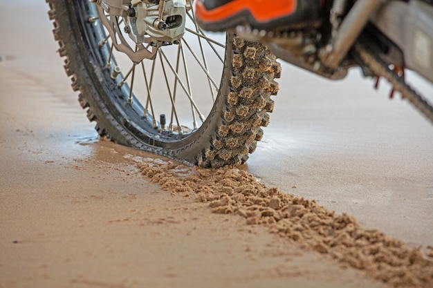 Motorwielen laten sporen achter in het natte zand op het strand