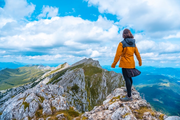 Mount Aizkorri 1523 meters, the highest in Guipúzcoa. Basque Country. Ascent through San Adrián and return through the Oltza fields. A young woman in yellow looking at the views on top