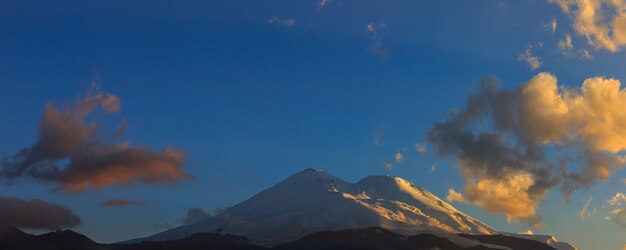 太陽の光の中で日没時にエルブルス山。ロシアの北コーカサス山脈のパノラマ ビュー。