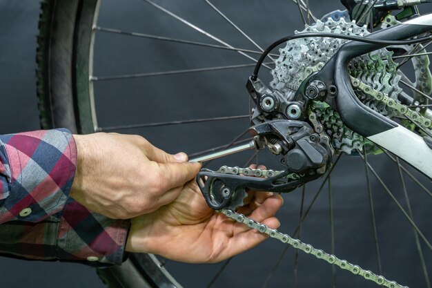 Mountain bike repair in the workshop Mechanic's hand and rear derailleur closeup Gearshift settings