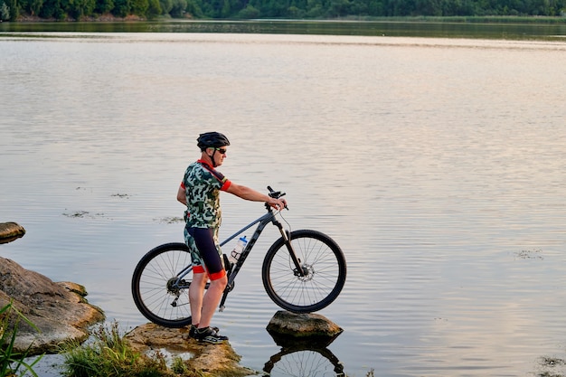 Mountain biker with a bicycle on a rock in a lake motivation
and inspiration for adventure extreme sport concept