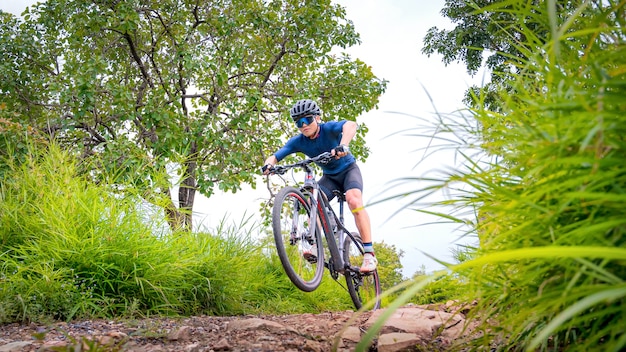 Маунтинбайкеры катаются на МТБ, горных велосипедах до крайности. Азиатский мужчина катается на MTB, маунтинбайке в дикой природе до крайностей. Экстремальный спорт и горный велосипед, концепция горного велосипеда.