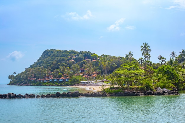 Mountain cape in the sea with holiday houses a small sandy beach on a tropical island Travel and tourism