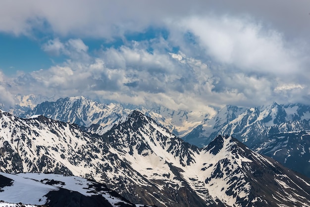 Mountain clouds over beautiful snow-capped peaks of mountains and glaciers. View at the snowy mountains.