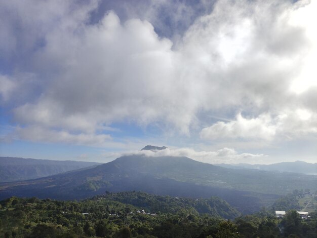 A mountain is visible behind a cloud that is in the sky.