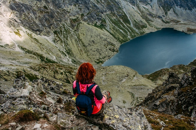 山の湖の美しい風景。高い岩。美しい風景。山の頂上に座っている女性を旅行します。