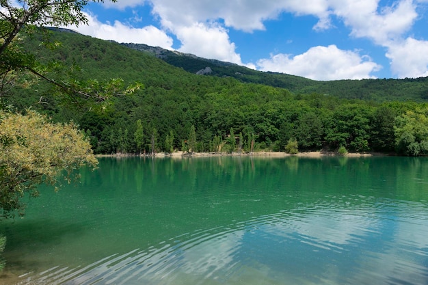 Mountain lake with turquoise water against the backdrop of mountains and a sky with clouds Landscape