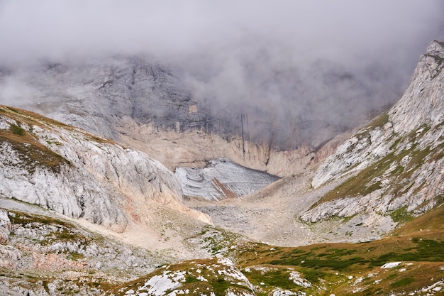 산 풍경 - 부분적으로 구름에 가려진 녹는 빙하가 있는 바위가 많은 고산 협곡