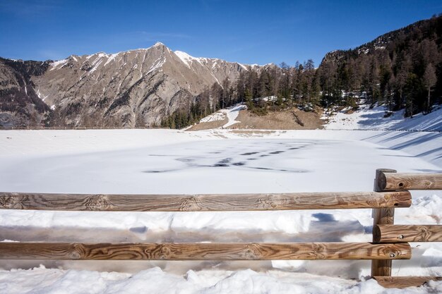 Mountain landscape under snow in winter and frozen lake