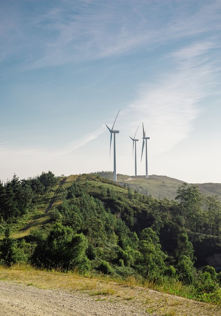 풍력 터빈이 전기를 생성하는 화창한 날의 산 풍경. 자연과 생태 에너지 생산 개념입니다.