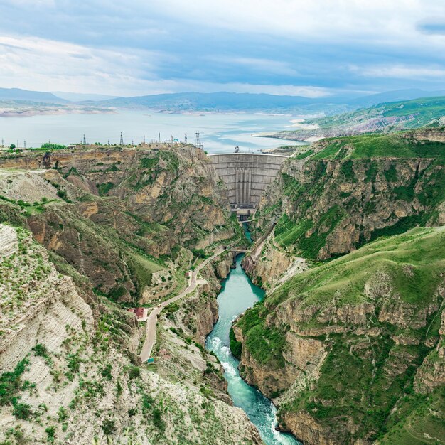 Горный пейзаж с арочной плотиной ГЭС и водохранилищем в долине