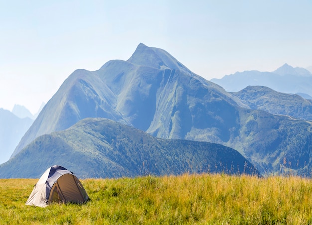 Mountain panorama with tourist tent. Sunrise or sunset in mountains. Hiking concept.