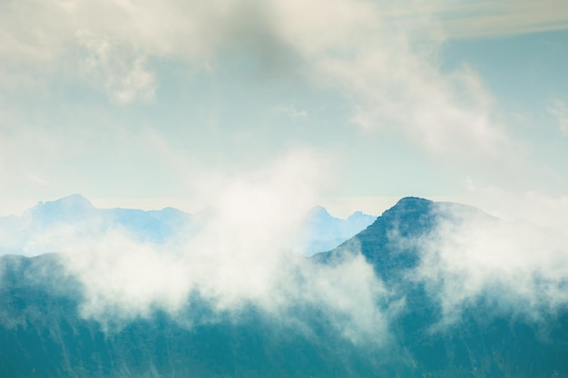 Mountain peaks with clouds in foggy morning. beautiful nature background. vintage filter