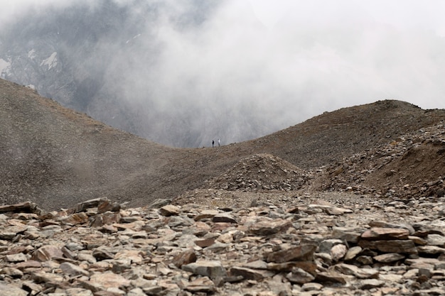 写真 雲の中の山脈。二人が尾根を歩いています。コーカサス、ロシア