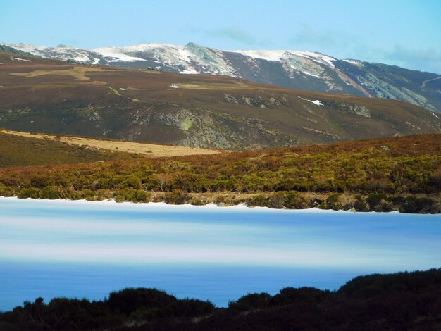 A mountain range is covered in snow and the blue water is surrounded by mountains.