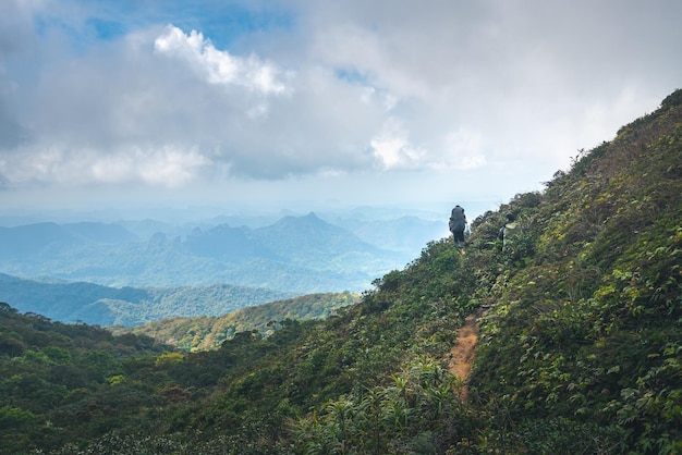 Mountain range landscape with sunshine during sunrise people\
trekking the mountain peak