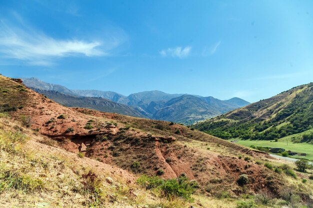 Photo a mountain range with a blue sky and a green field