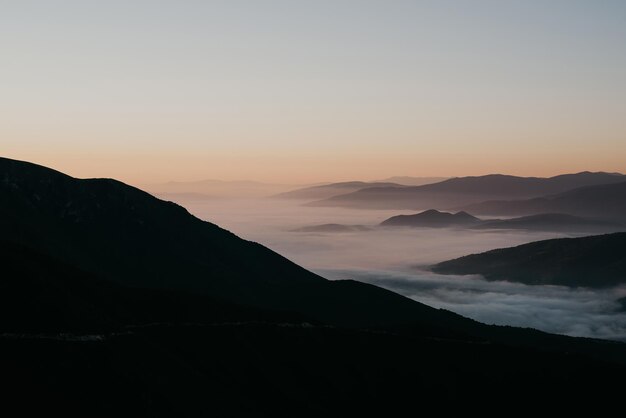 Mountain range with visible silhouettes through the morning colorful fog