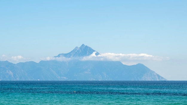 Mountain reaching clouds in the distance with Aegean sea on the foreground in Greece