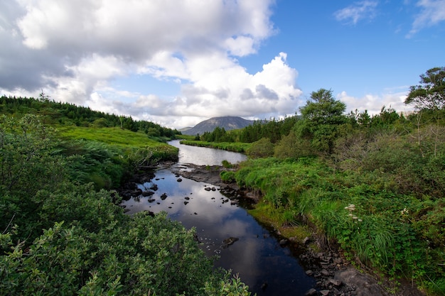 Mountain river creek landscape with clouds covered mountain in the distance.