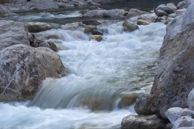 A mountain river flowing down from the mountains along a rocky shore