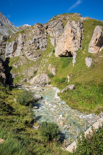 Mountain river and wood bridge in Vanoise national Park valley French alps