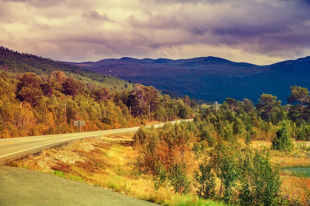 Mountain road at sunset with dramatic cloudy sky Beautiful nature Norway Colorful autumn Mountain landscape