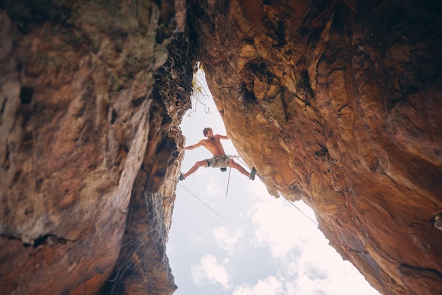 Arrampicata in montagna o arrampicata su roccia e drogato di adrenalina con coraggio nell'avventura cercando di bilanciare il divario uomo di scalatore atletico che fa esercizio di fitness e allenamento durante gli sport estremi