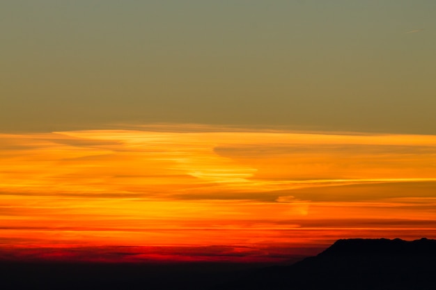 イタリアアルプスからの赤い夕日の山のシルエット。雲の背景